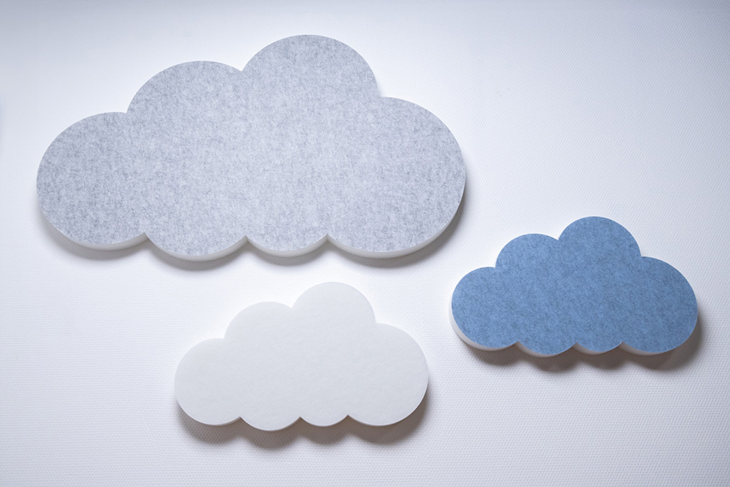 Three sound absorbers in the shape of a cloud in blue, white and light gray on a white wall.