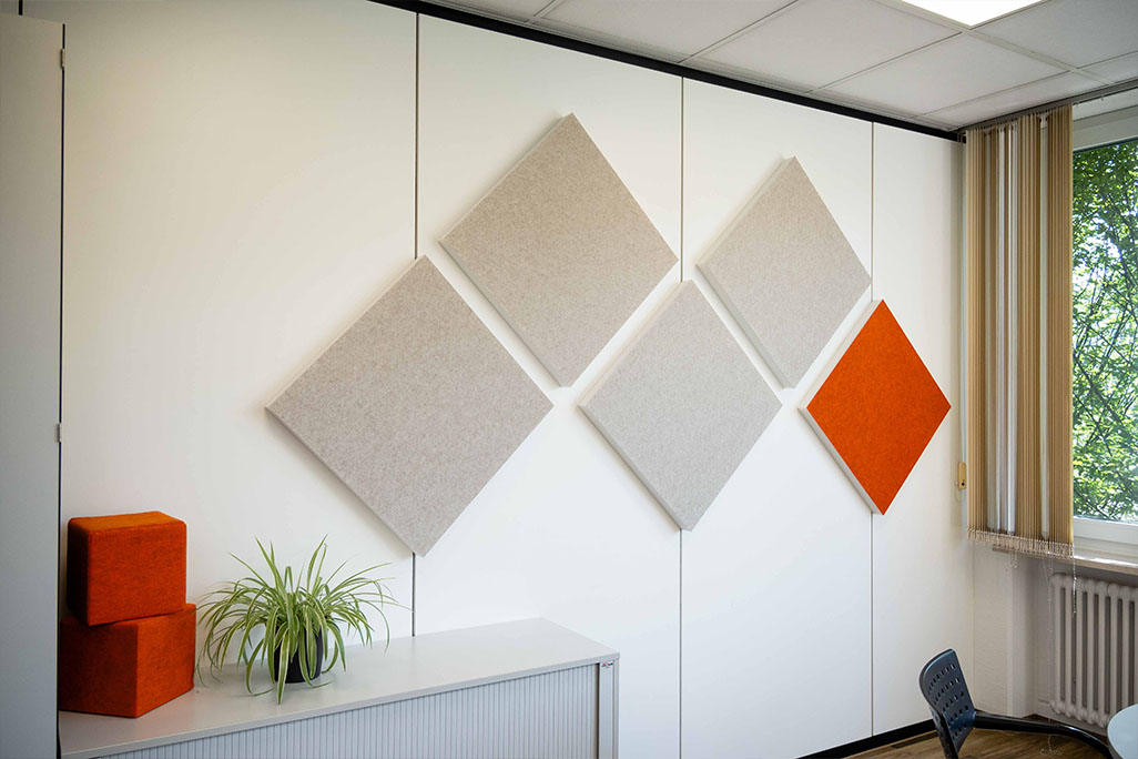 Bright office with a meeting corner and 5 square wall absorbers in greige and orange